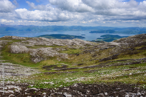 Foto An expansive view descending into a verdant, rocky mountain valley within Galicica National Park, culminating in the serene blue waters and distant shores of Lake Prespa