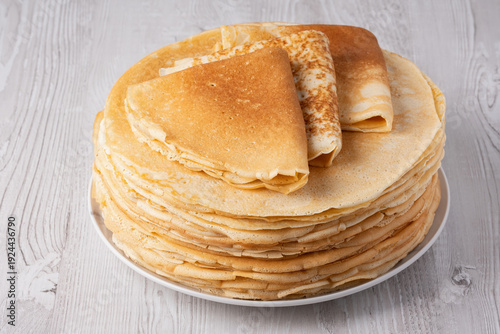 Thin pancakes on a wood table. Homemade crepes, tasty food. Staple of yeast pancakes, traditional for Russian pancake week (Shrove tide). Thin pancake with crispy crust