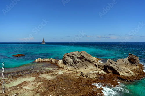 Sailboat sailing near rocky coastline in cancun mexico caribbean sea
