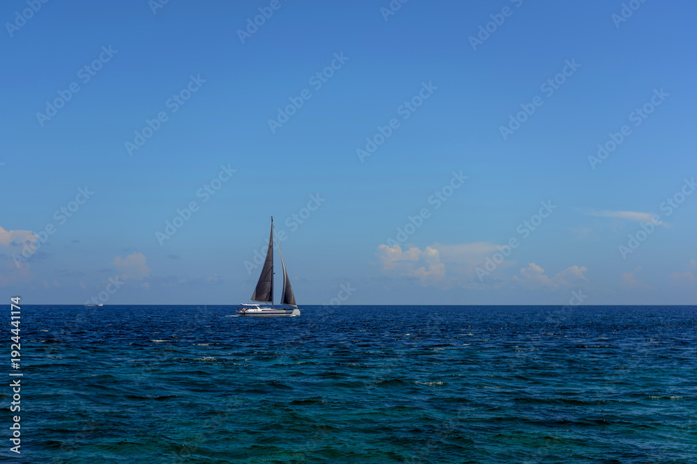Obraz premium Sailboat on open blue ocean under clear sky in mexico caribbean