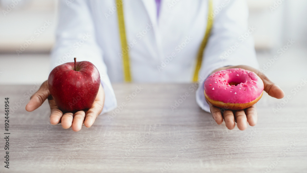 Αυτοκόλλητο A person holds an apple in one hand and a pink frosted donut in the other hand in a setting focused on health choices