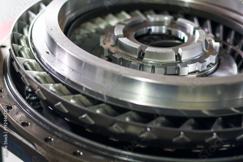 Close up high angle of a shiny metallic turbine engine component with intricate mechanical details and precision engineering parts in a workshop.