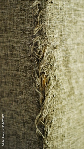 Close up of torn fabric upholstery with visible scratch marks and frayed threads caused by cat claws. Damaged textile surface showing wear and tear, suitable for pet behavior, home damage, and texture