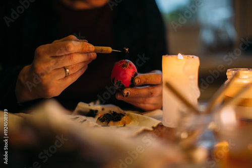 Person decorating traditional pysanky easter egg with wax