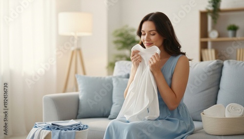 Happy woman smelling fresh clean laundry while sitting on a sofa at home