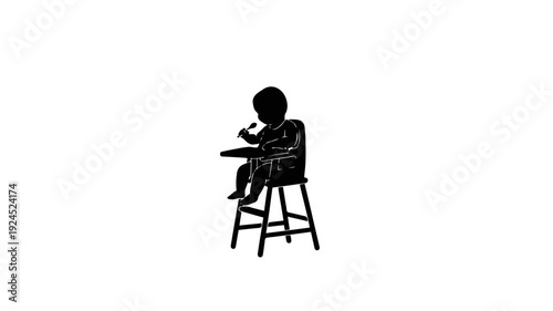 Silhouette of a baby sitting in a high chair eating.