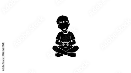 Silhouette of a young boy playing video games cross-legged.