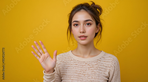 Young deaf mute woman using sign language on color background