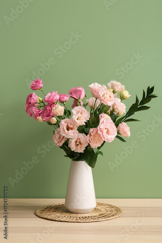Vase with beautiful eustoma flowers on wooden table in living room
