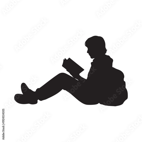 Silhouette of a young man sitting and deeply engrossed in reading a book