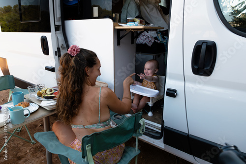 Mother feeding baby breakfast during camper van trip
