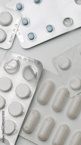 Numerous blisters with multicolored pills and tablets rotating on a white background, symbolizing healthcare, pharmaceutical industry, and medication concepts for medical treatment
