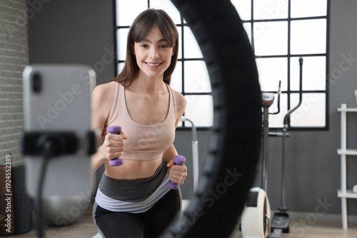Sporty female blogger recording aerobics video in gym