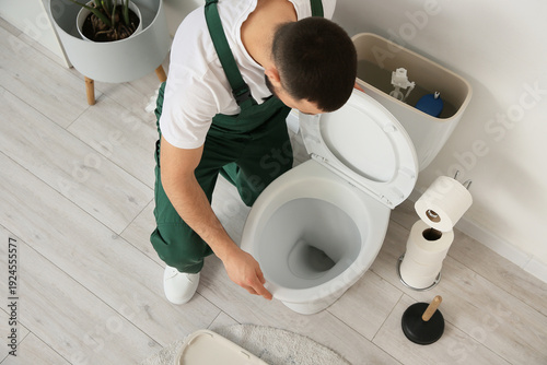 Male plumber repairing toil...