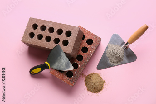 Trowels and bricks on pink ...