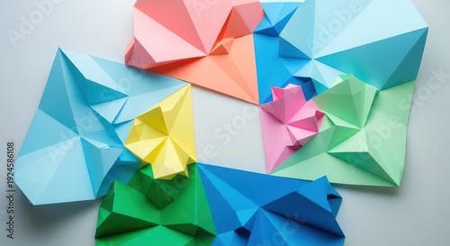 Five colorful geometric paper constructions arranged on a neutral surface