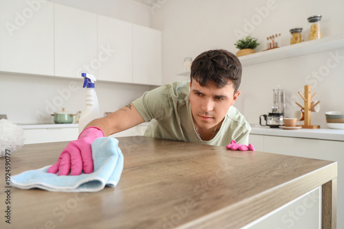 Young man cleaning table in...