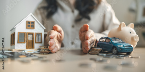 Foto Hands protecting house and car models with savings and piggy bank, symbol of personal finance, asset protection, insurance planning and long term wealth management