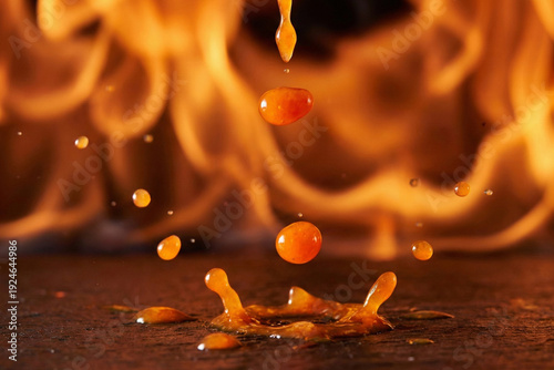 Spicy Hot Sauce Drops Splashing on a Dark Surface with Fire Background