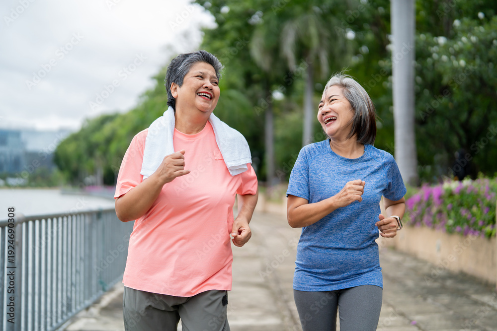 Obraz premium Two happy Asian senior women jogging exercise outdoors in modern city.