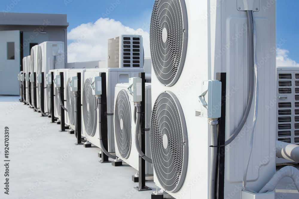 Obraz premium Air conditioning (HVAC) on the roof of an industrial building with blue sky and clouds.