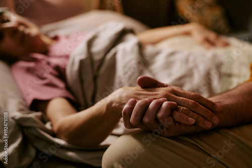 Tableau sur toile Senior Caucasian woman lying in bed holding hand of senior Caucasian man, showin