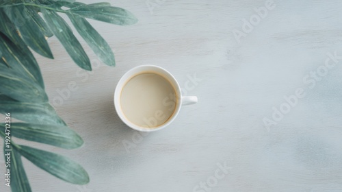 White coffee cup with a leaf on the table