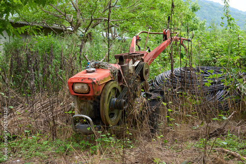 Abandoned old farm machine in overgrown rural nature