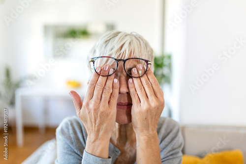 Tableau sur toile Mature woman with glasses rubbing her tired eyes at home