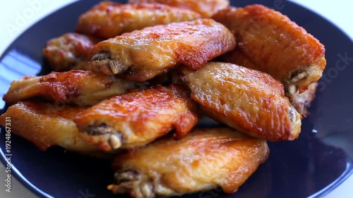 Chicken wings marinated in dark soy sauce, fried in vegetable oil until crispy, arranged on a black square plate
