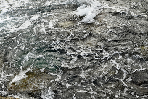 Foto Close-up of a dark, crashing sea wave with white sea foam and spray