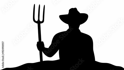 Farmer in silhouette holding pitchfork in field