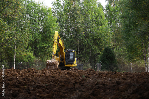 Excavator in Action: Heavy Machinery Digging in Verdant Forest Clearing