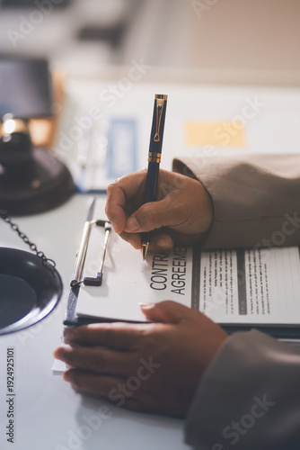Judge gavel with Justice lawyers having team meeting at law firm in background. Notary with client in office