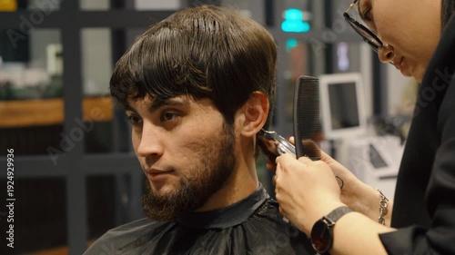 Barber shaping sideburns of a man with electric shaver