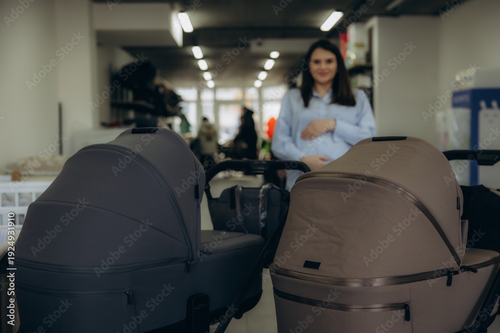 Fototapeta premium Pregnant woman choosing modern baby strollers for newborn