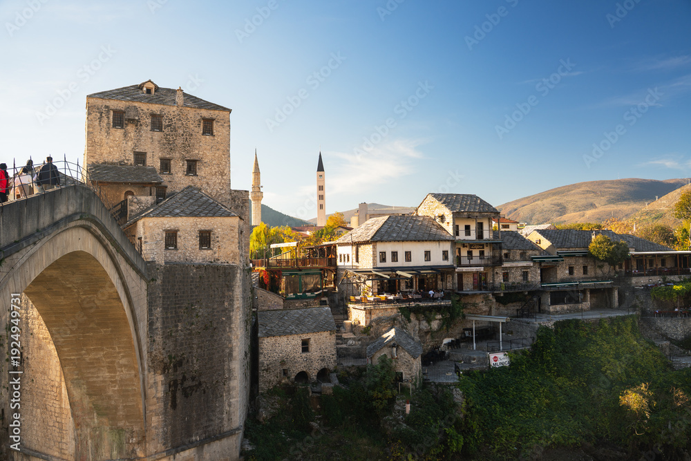 Fototapeta premium Historic stone arch bridge in mountain river valley during sunny morning side light. 