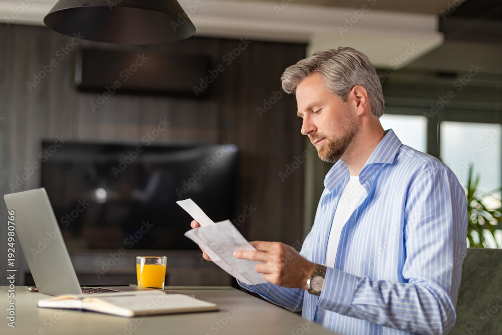 Fototapeta premium Serious businessman concentrated reading from whom letters, received a bad news, male manager employee unpacking banking notification.