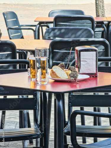 A restaurant terrace table with drinks and bread and some sparrows eating it