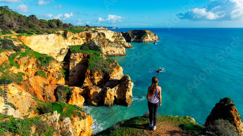 hapy woman enjoying the panoramic top view of rocky beaches with cliffs, Algarve in Portugal