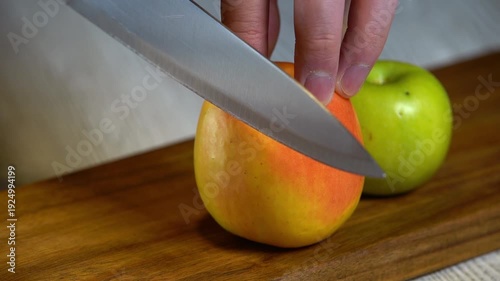 Cutting a red apple with a knife on an authentic wooden board