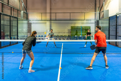 People playing pickleball doubles match on indoor court