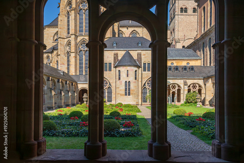 Cloister courtyard view at Trier Cathedral in Trier, Germany, framed by arches and columns; UNESCO World Heritage site with historic church architecture and garden.