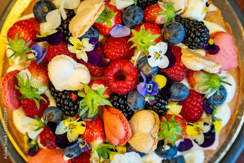 Billede på lærred Tarte aux fruits rouges, macarons et fleurs comestibles, une création sucrée gourmande et colorée