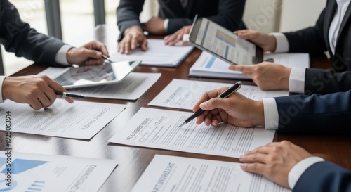 Business team reviewing contracts and digital data at meeting