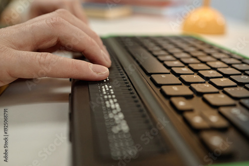 Fotografi Caucasian adult hand reading braille display on keyboard in library, fingers mov