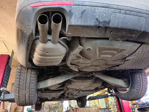 Obraz na płótnie Underside view of a car on a lift, showing exhaust system and suspension compone