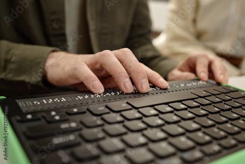 Cuadro en lienzo Caucasian young adult man reading braille display with both hands in library set