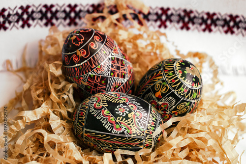Traditional hand painted wooden Easter eggs with Ukrainian folk designs on decorative paper background. For Easter, spring holidays, culture and concept of handicrafts.