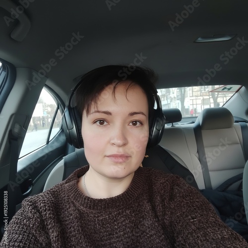 A woman wearing headphones listens to music while sitting in a car. Realistic image, transportation, technology, entertainment, portraits